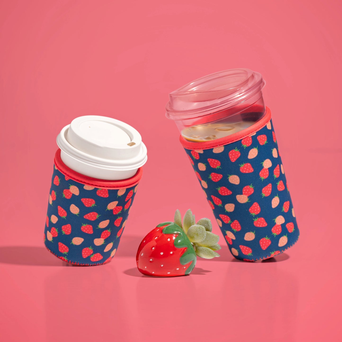 Strawberries small and large drink sleeves in use with strawberry shaped succulent pot with a pink background.