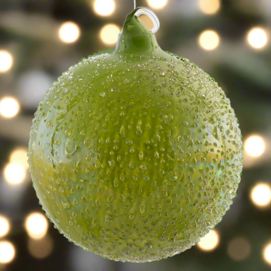 Iridescent Icy Glass Ball Ornament with holiday lighting in the background.