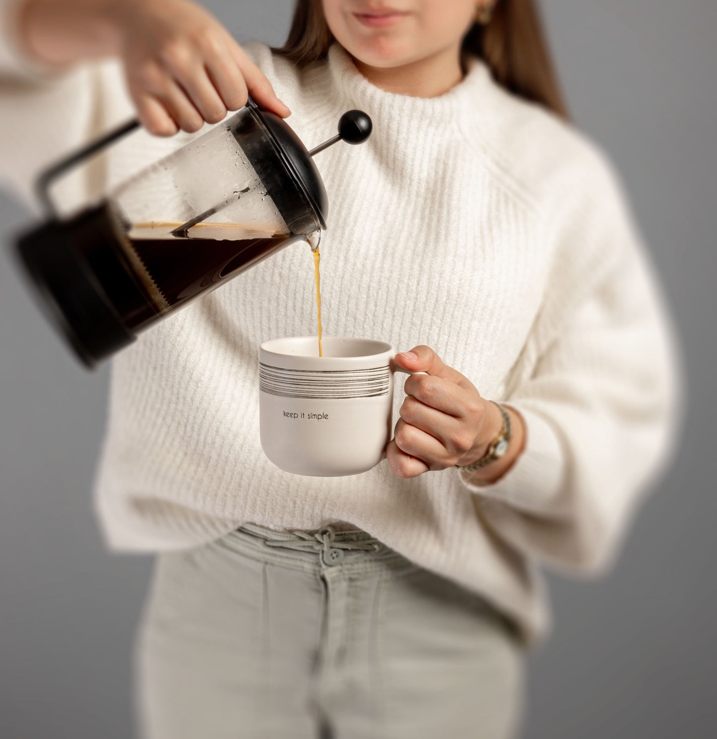Woman holding milo mug and pouring coffee into it.