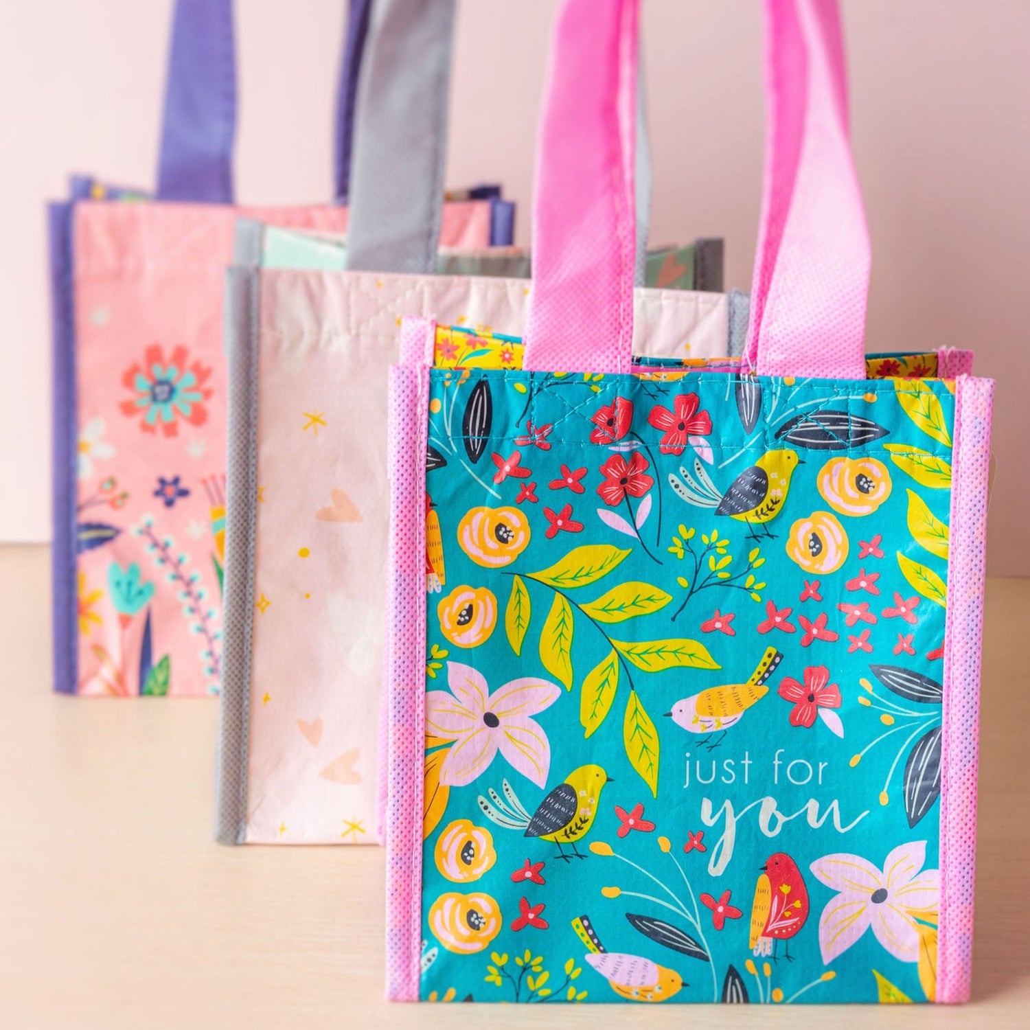 Just for you, enjoy, and hooray small recycled gift bags stacked on a table.
