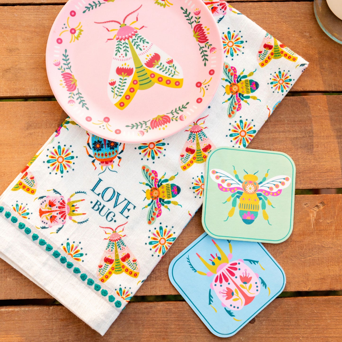 Bugs pulp paper coasters, bugs melamine plates, bug tea towel on a table.