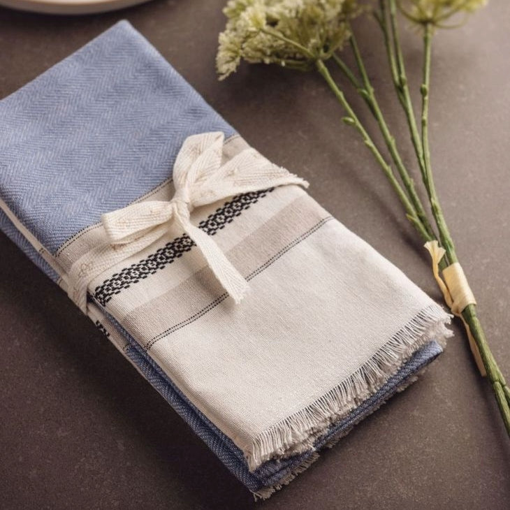Periwinkle Lisbon Dinner Napkins on a counter with floral accents.