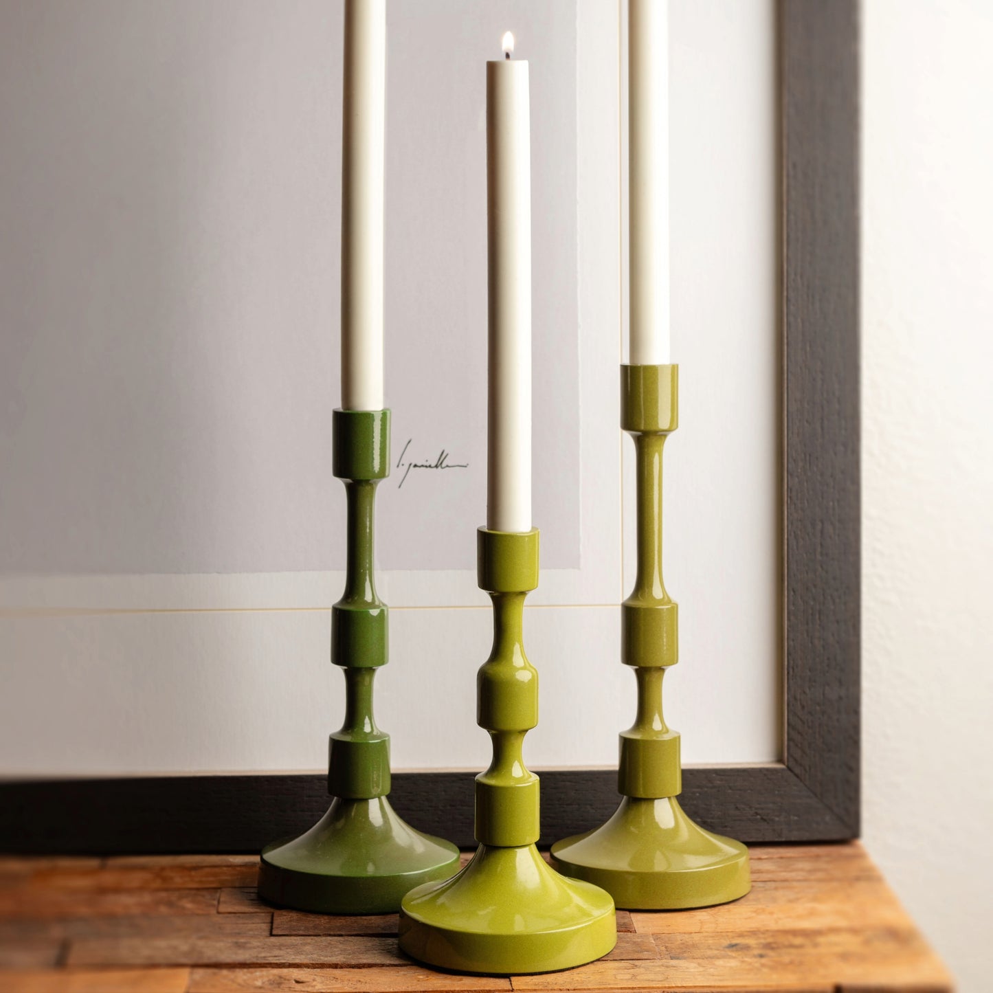 Metal taper candlestick holders on a wooden table.