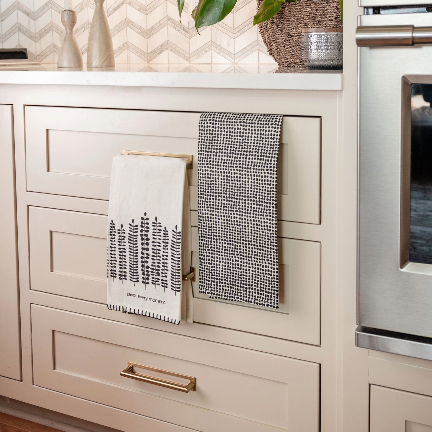 Savor Every Moment Modern Farmhouse Tea Towel Set of 2 hanging on cabinets in a kitchen.