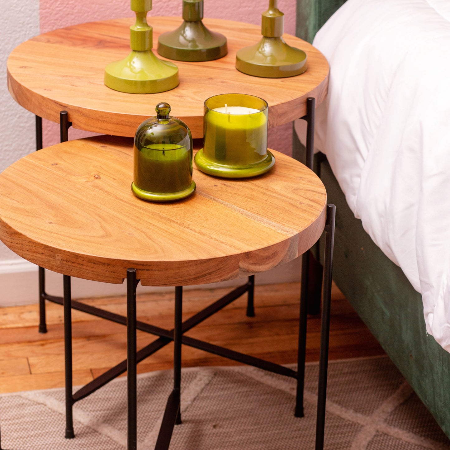 Round Nesting Tables next to a bed with candles on top of them.
