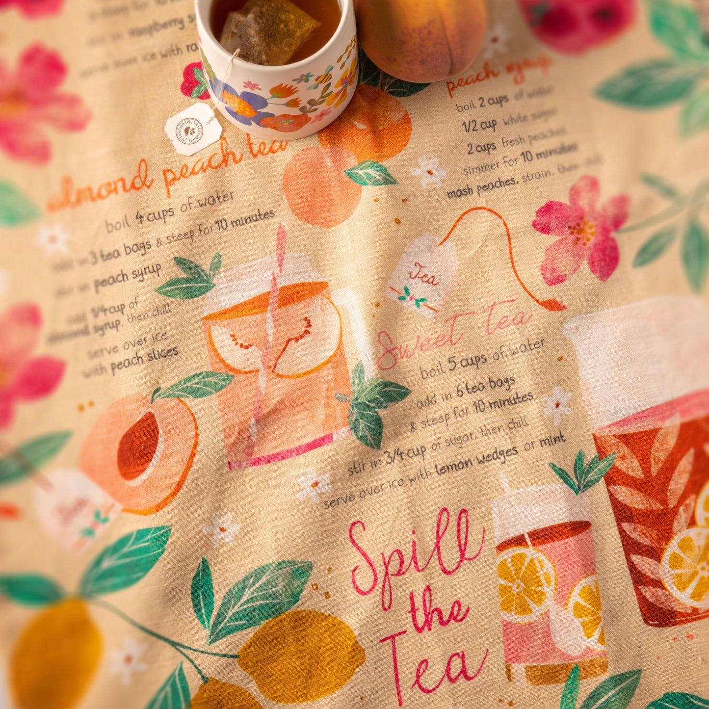 Sweet Tea Tasty Tips Tea Towel on a table with a mug and a peach.