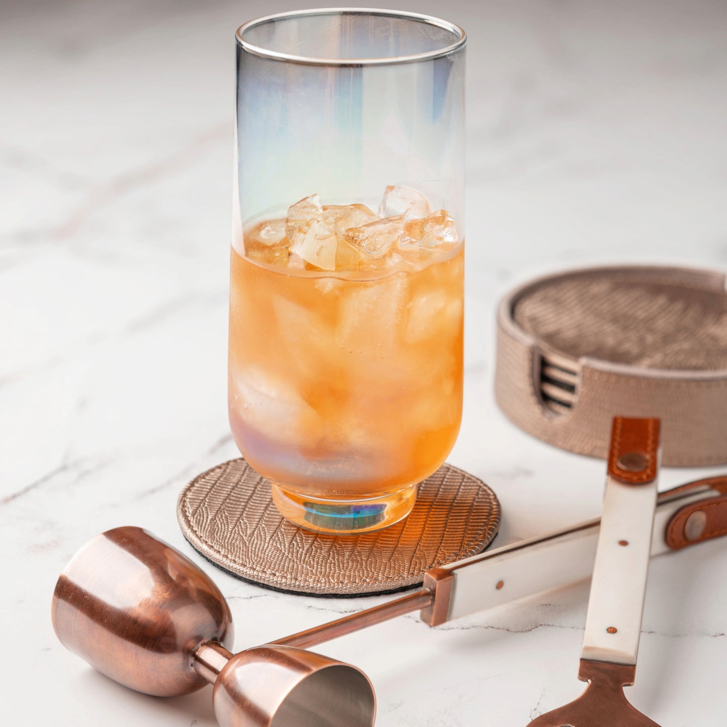 Metallic Pewter Faux Leather Coasters with Holder on a table with a drink.