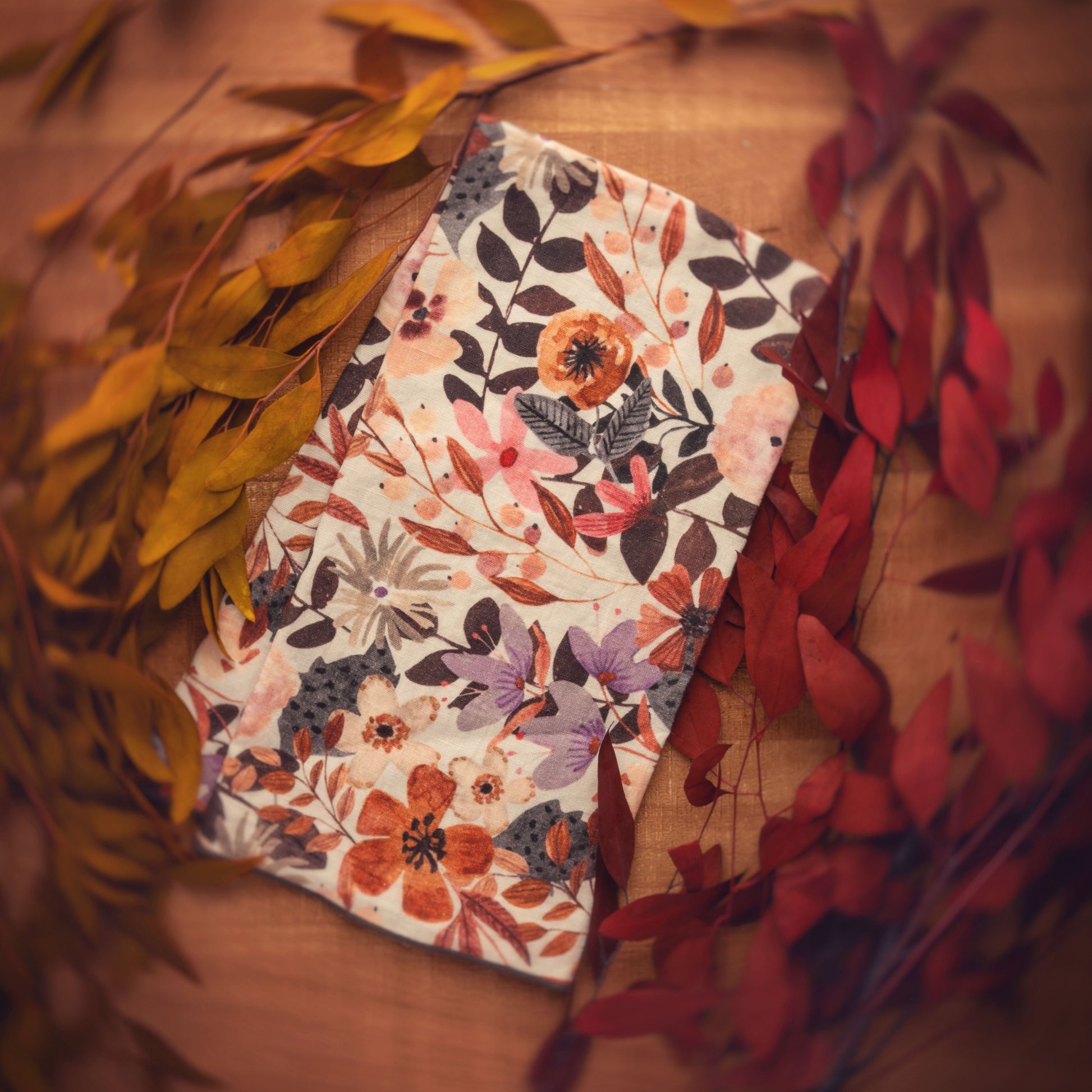 Cinnamon Floral Linen Blend Tea Towel on a table with foliage accents. 