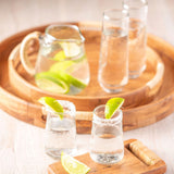 Boardwalk round trays with a pitcher and cups on them. 