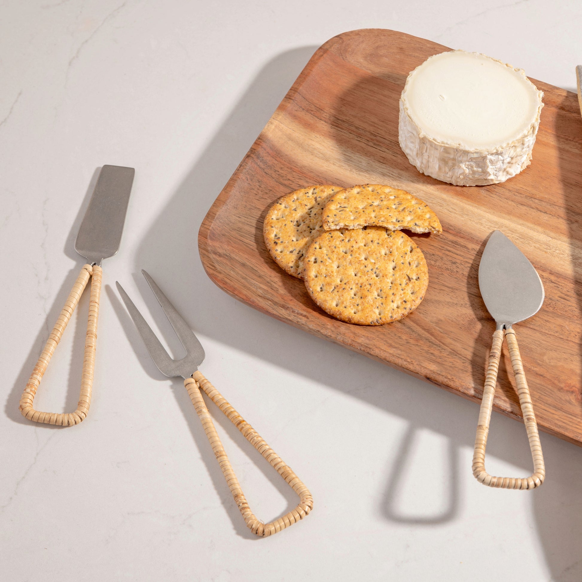 Catalina Cheese Tools on a counter. Serving board with crackers and cheese beside them. 