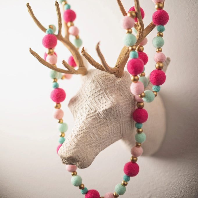 Felt garland hanging on a fake deer head on the wall. 