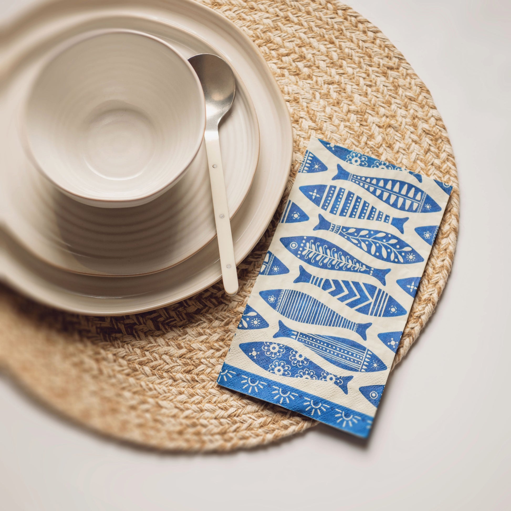 Fish guest towel paper napkin on a placemat next to a table setting. 