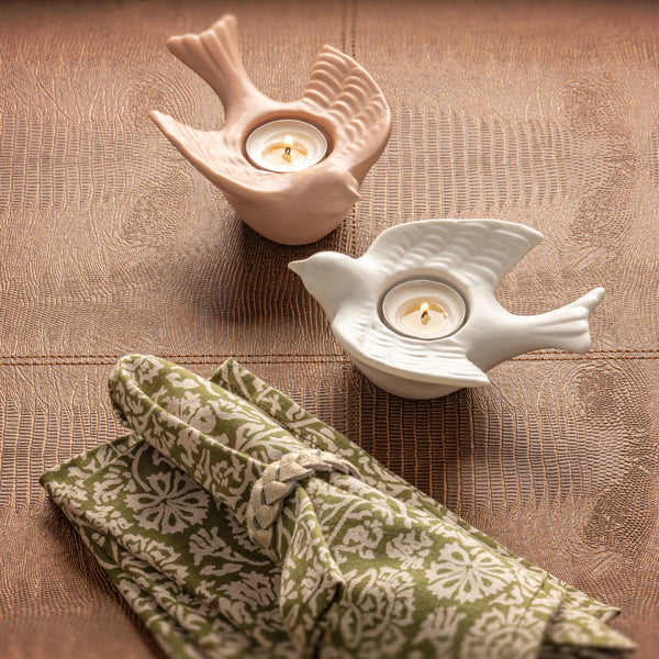 Bird tealights on a table next to a tea towel